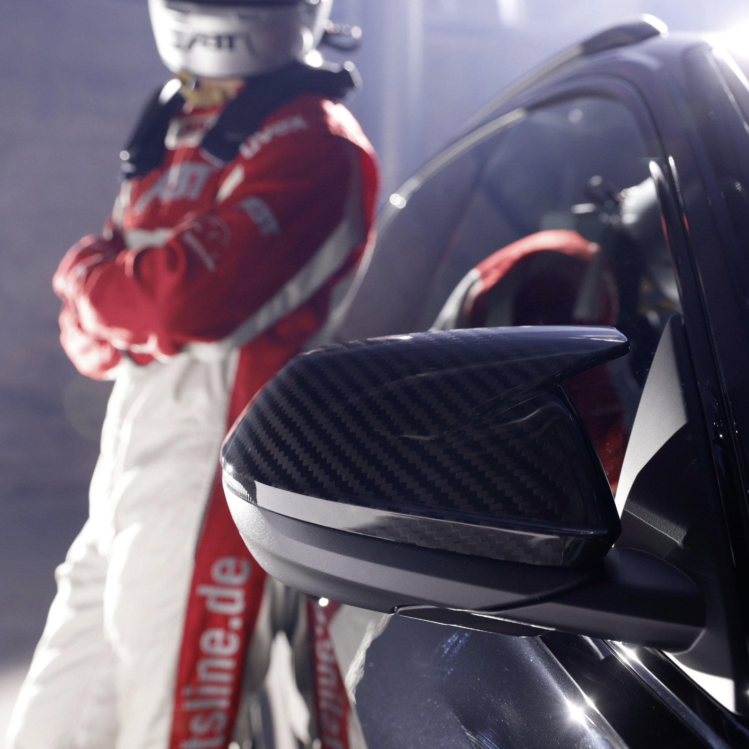 Racing driver leaning against black RSQ8 Signature Edition, close-up of mirror cap